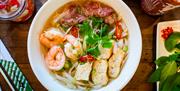 Bowl of pho with noodles, prawns and garnish