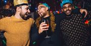 People talking to each other with drinks in hand and festive crowns on heads