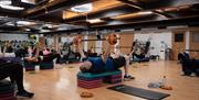 A group of people taking part in a fitness class inside the YMCA Bath Gym.