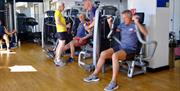 People using the fitness equipment inside the YMCA Bath Gym.