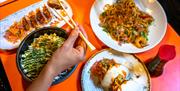 Dishes at Yakinori and a hand holding a pair of chopsticks