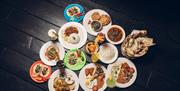 Overhead shot of plates of food from around the world on a black panelled floor