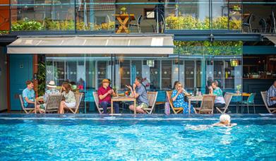 Bristol Lido - person swimming in pool and people dining by restaurant