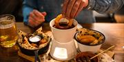 Person dipping an onion ring into gravy fondue