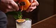 Cocktail being decorated with orange peel